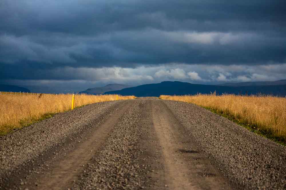 Gravel road in Iceland Gravel road in Iceland under dark storm clouds, highlighting challenging driving conditions.