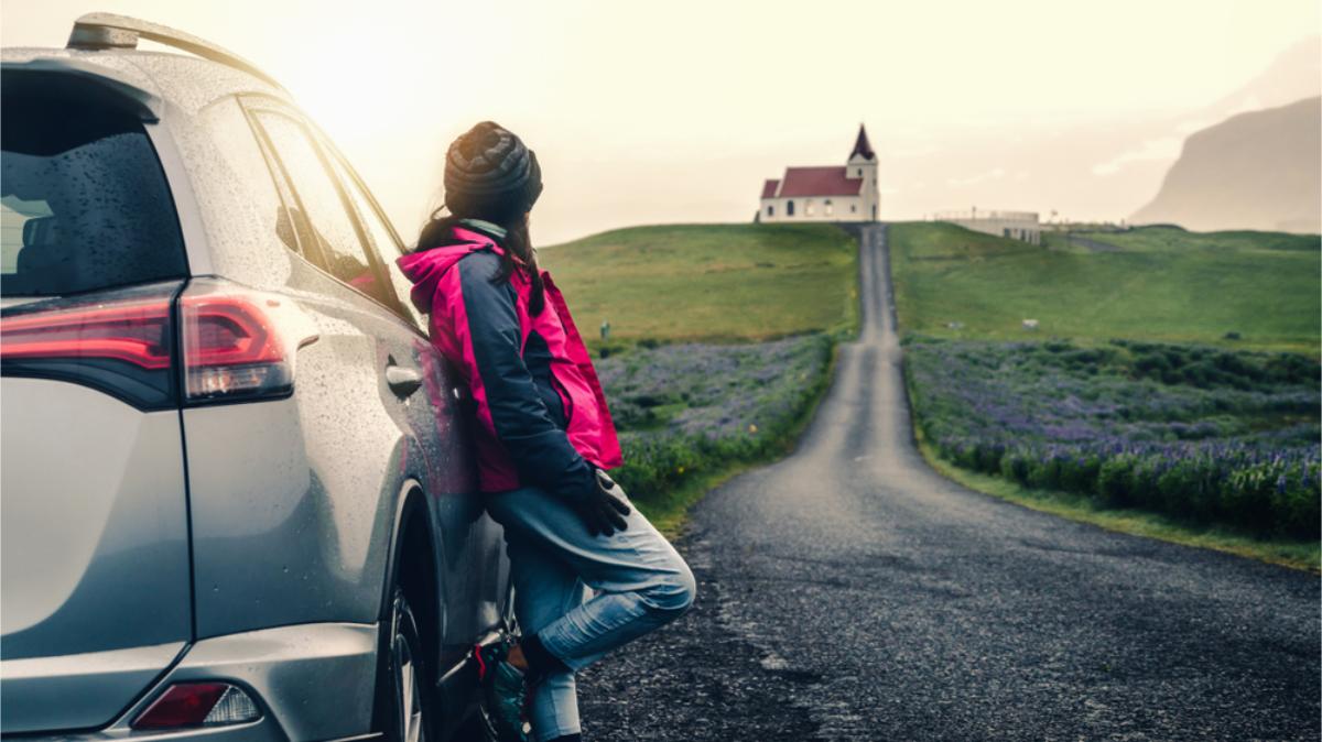 4x4 car rental in Iceland woman watching a red roof church that's on top of a hill