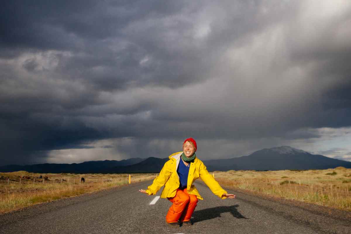 What to know about kilometer road tax Traveler kneeling on an empty road in Iceland under dramatic dark storm clouds