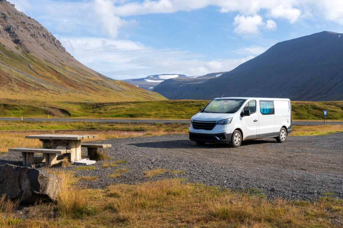 Rental car vs campervan in Iceland. What should you choose? White campervan parked at a scenic pull-off in Iceland surrounded by mountains and wide valley views