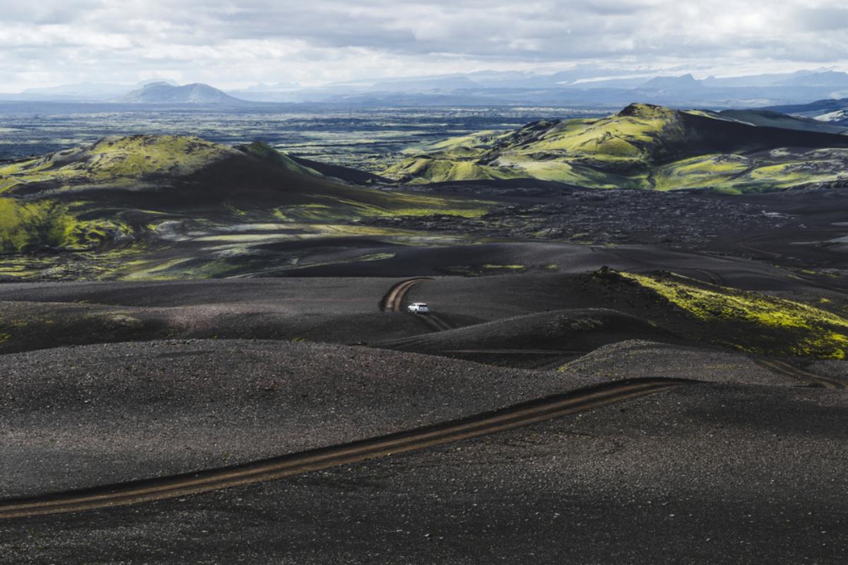 Protection contre le sable et les cendres : que couvre-t-elle ? Route dans les Hautes Terres d'Islande couverte de cendres volcaniques noires et un véhicule circulant dessus