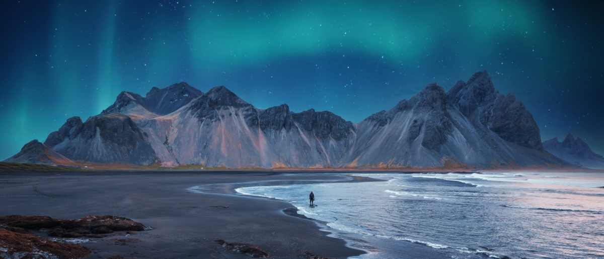 La montagne Vestrahorn et la plage de sable noir Reynisfjara &agrave; son pied en Islande sous une aurore bor&eacute;ale.