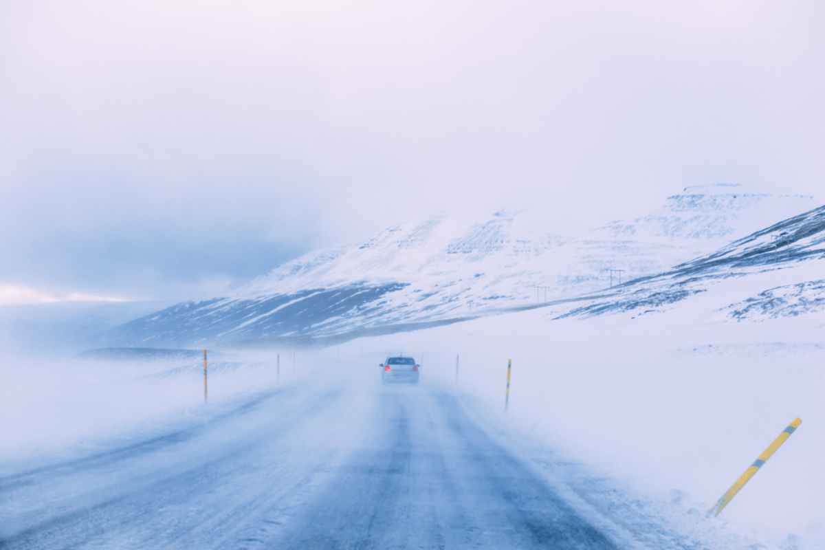 Winter in Island: Gemeinsame Herausforderungen für Autofahrer Graues Kompaktfahrzeug mitten in einem Schneesturm auf Islands Ringstraße