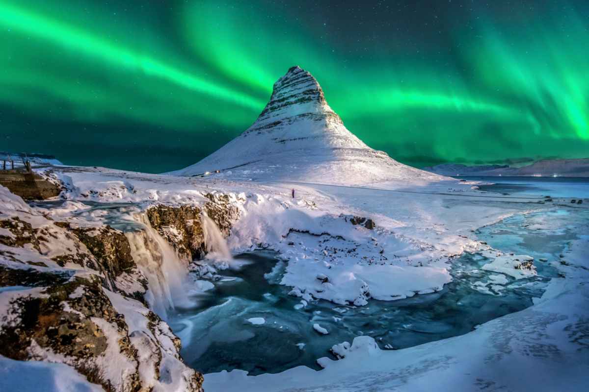 Sichere Winterrouten für Anfänger Der Kirkjufell-Berg im Winter mit Nordlichtern am Himmel