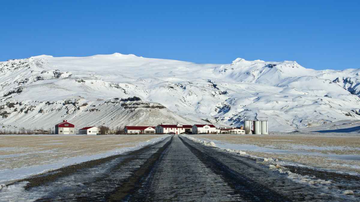 Stra&szlig;e, die zu einem Bauernhof in der N&auml;he des vulkanischen Eyjafjallaj&ouml;kull f&uuml;hrt, bedeckt mit Schnee