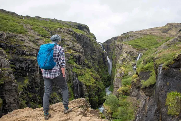 Mann beim Wandern am Glymur-Wasserfall in Island Wanderer, der die Aussicht auf den Glymur-Wasserfall genießt