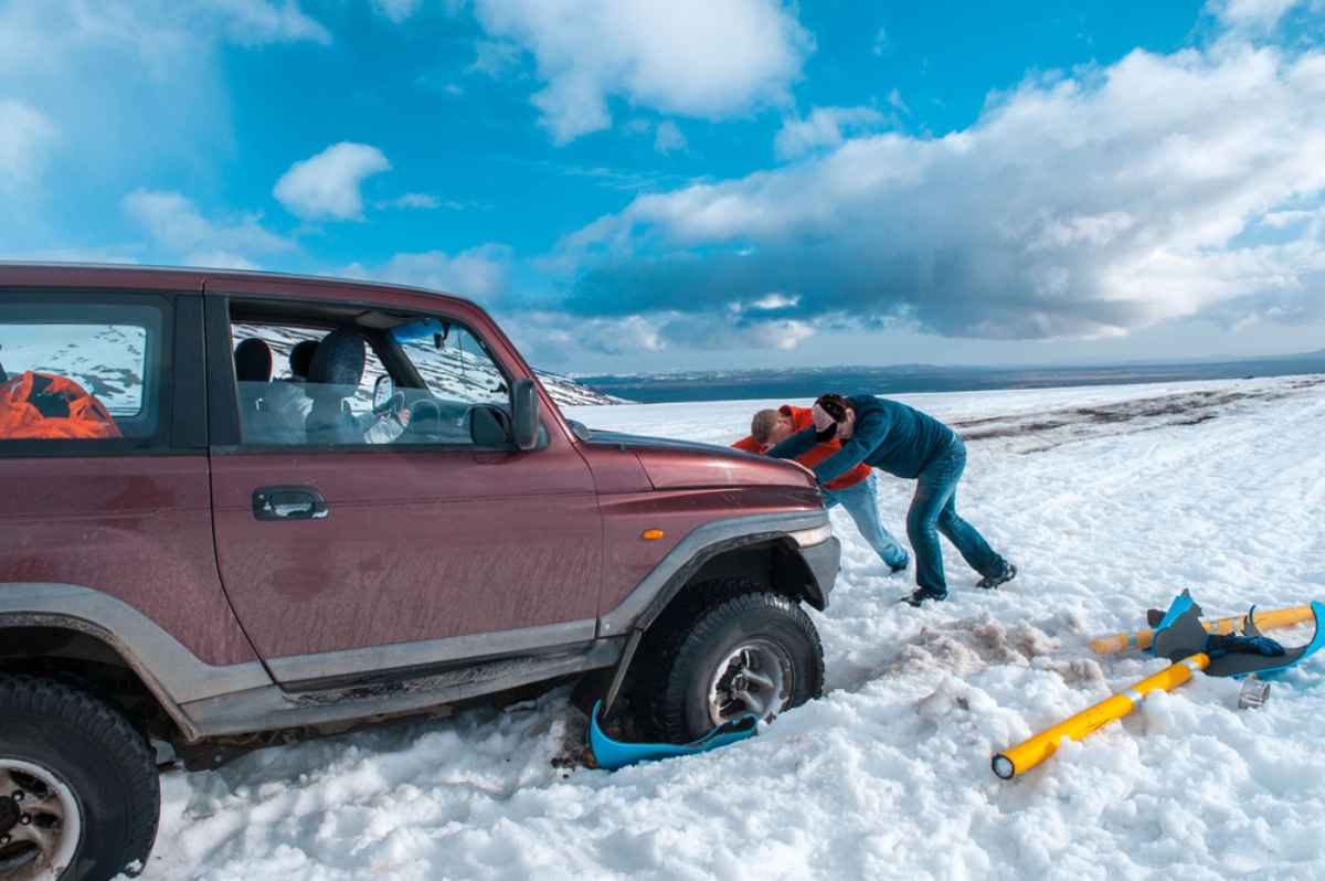 Un grupo de personas ayuda a remolcar un coche tras quedar varado en la nieve