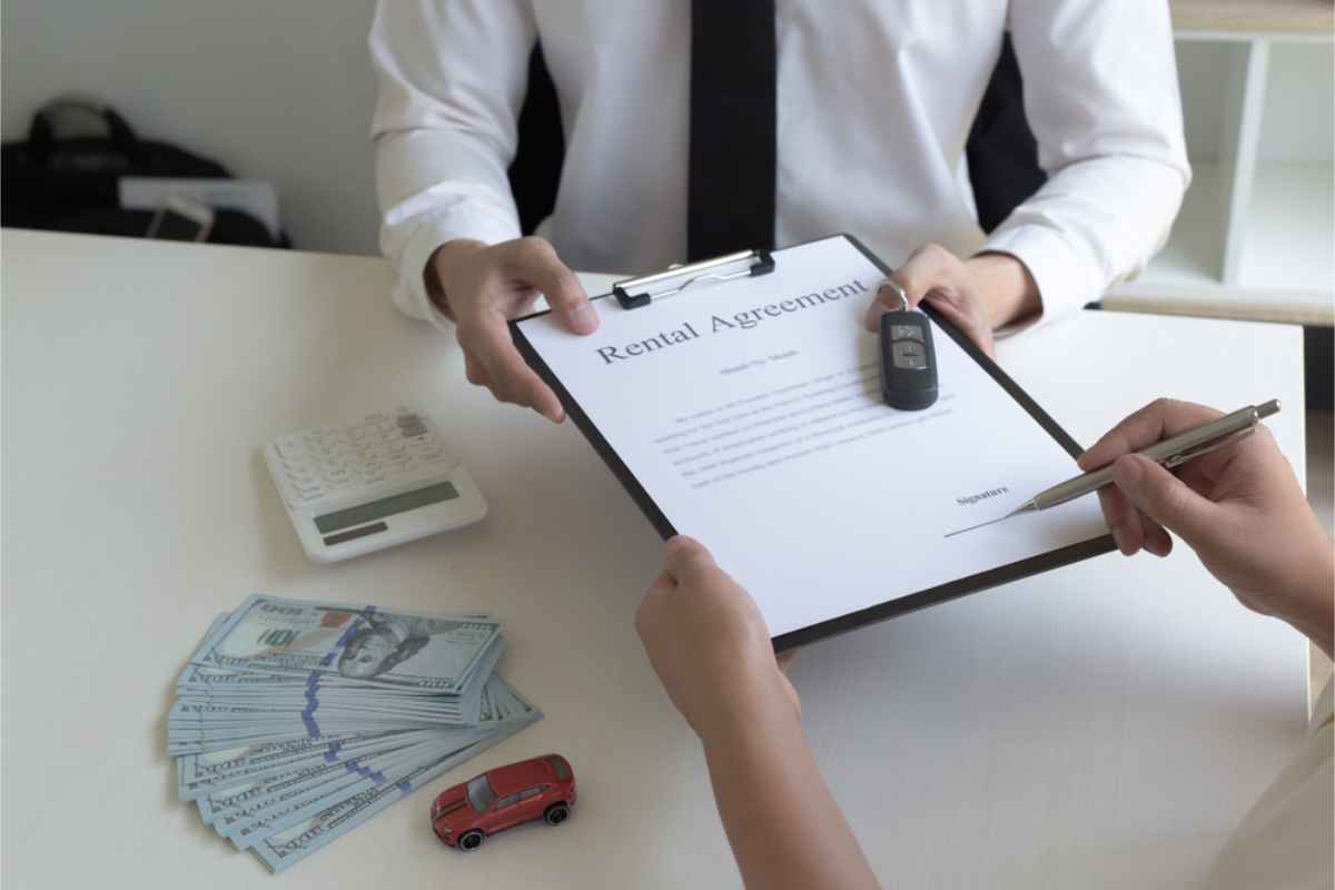 Client signing his rental agreement at the car rental office with cash on the table