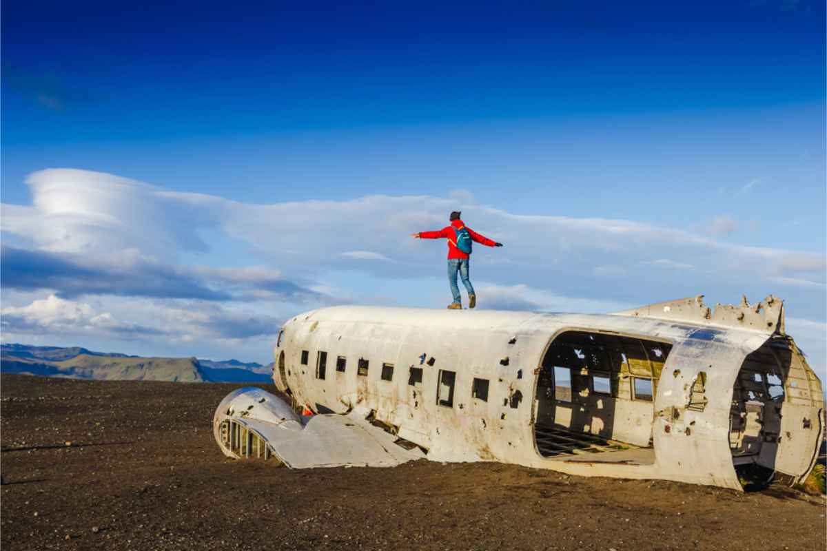 Turista sobre los restos de la nave en Solheimasandur