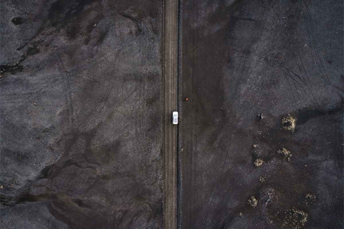 Voiture de location sur une route traversant un champ de lave en Islande