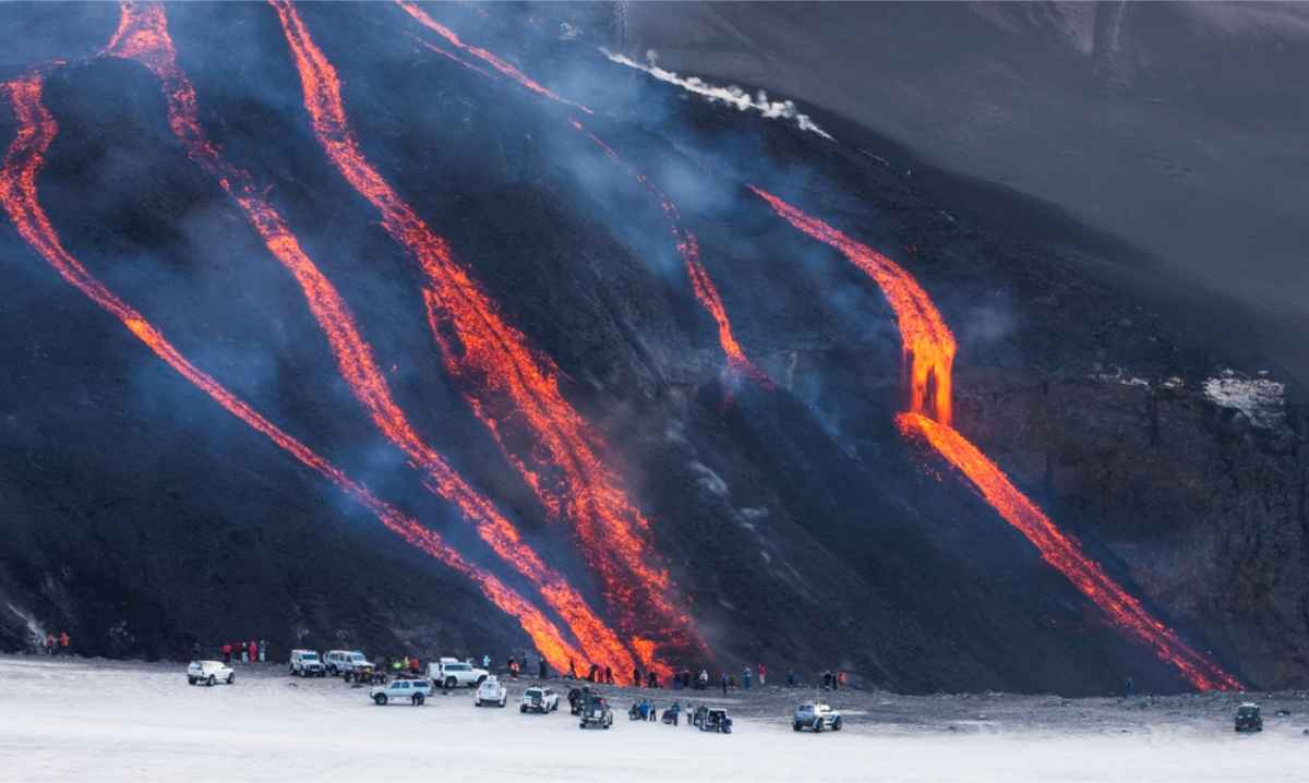 Touristen und Rettungskräfte beobachten einen Lava­fluss aus sicherer Entfernung