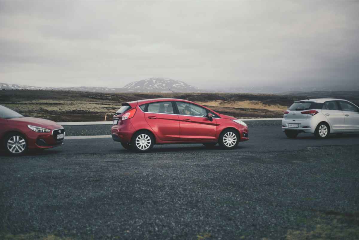 Red compact Kia Rio car parked with a beautiful view of Iceland's landscapes