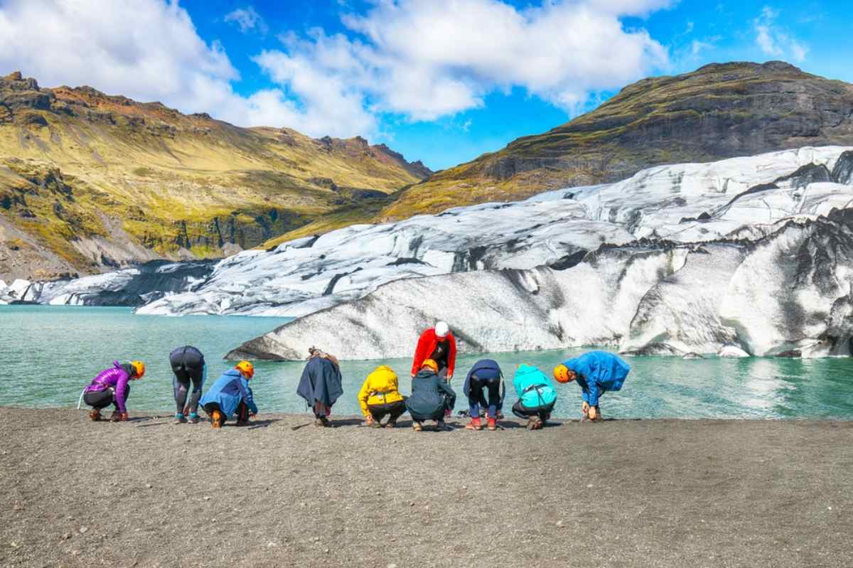 Group of travelers preparing for a guided glacier hike in Iceland near a lagoon.