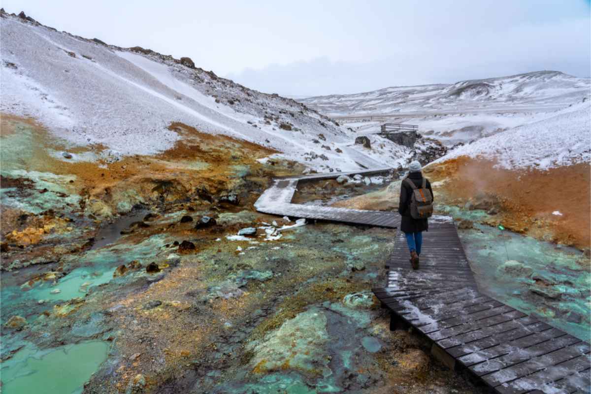 Tourist walking on a wooden platform in the middle of a geothermal area