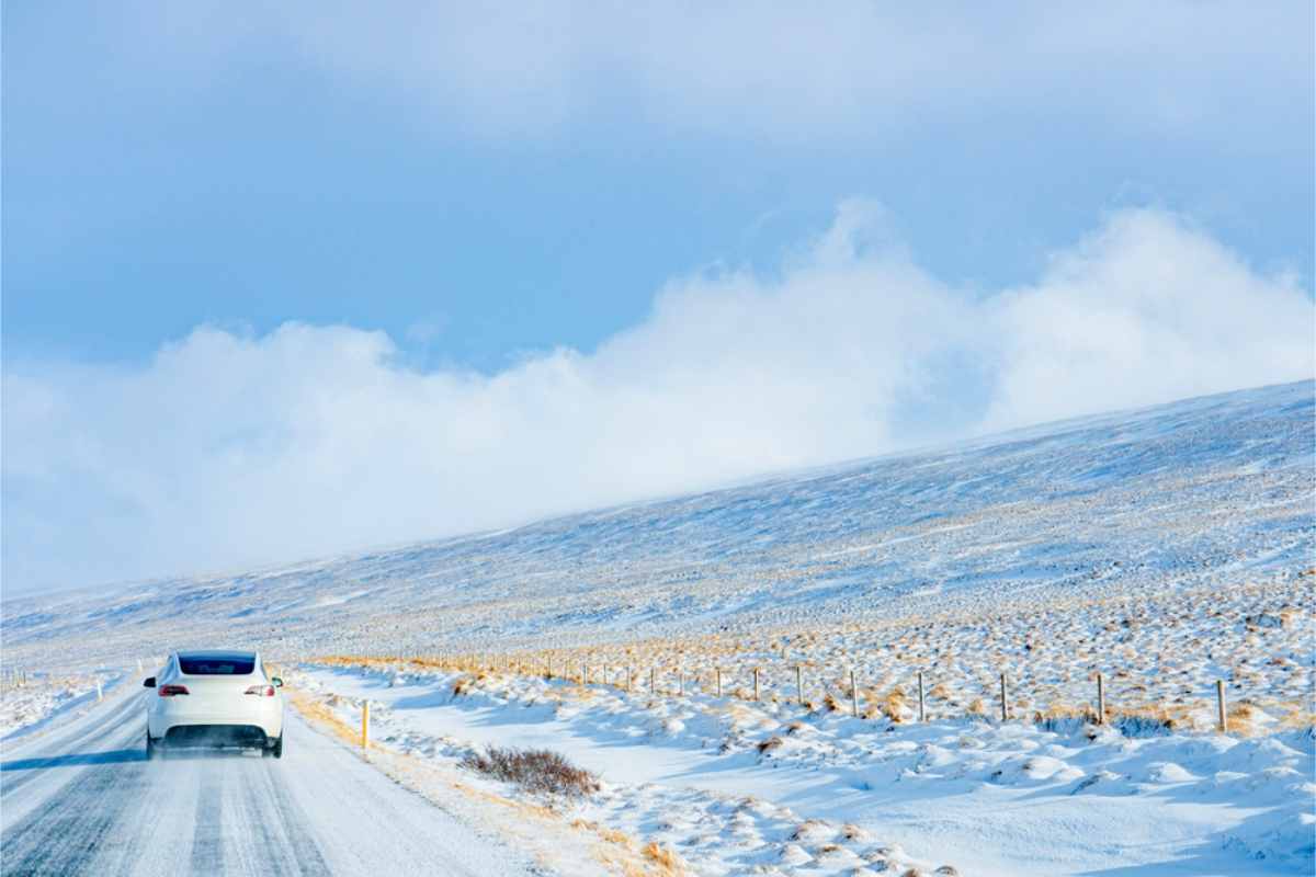 Iceland road conditions during winter White tesla driving in a snow covered road
