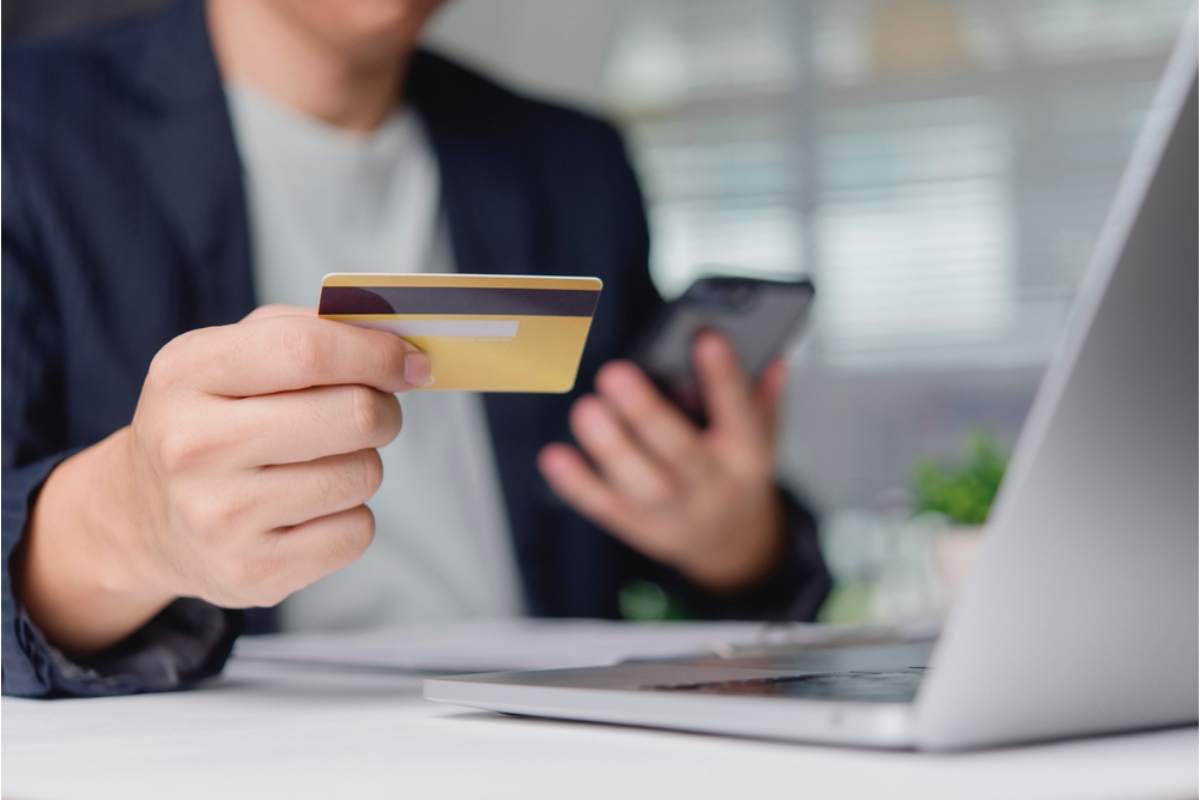 Person holding a credit card and phone while booking or paying for a rental car in Iceland