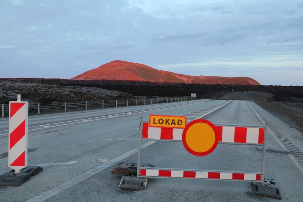 Road closure barrier blocking a highway in Iceland with volcanic landscape in the background
