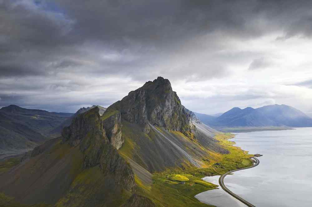Dramatic mountain ridge beside a winding coastal road in Iceland.