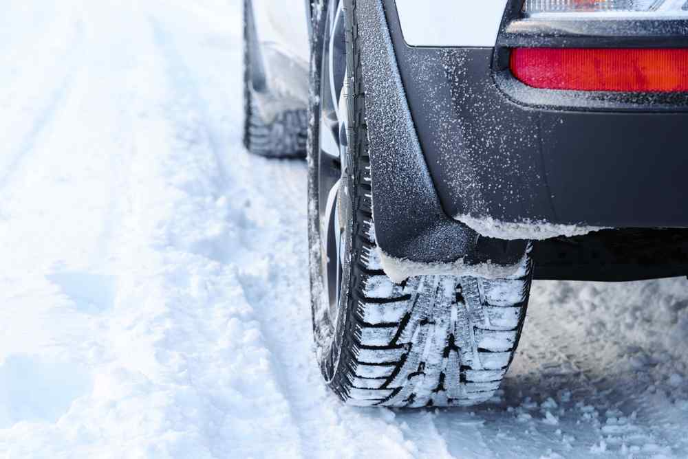 Close-up of a winter tire gripping a snow-covered road.