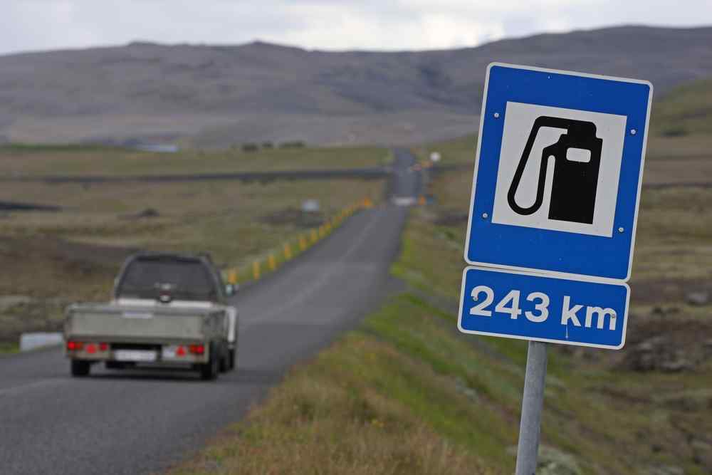 Fuel distance in Iceland Roadside fuel sign showing the next gas station is 243 km away on a remote road through Iceland’s open countryside.