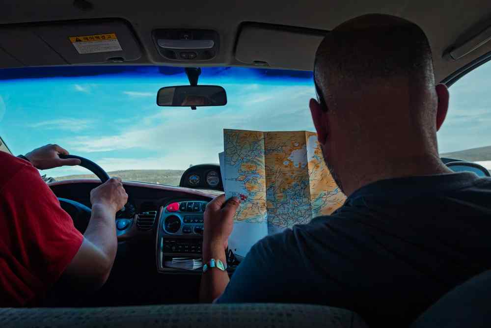 Driving in Iceland with an offline map Passenger checking a paper map while travelling by car in Iceland, highlighting the value of offline navigation.