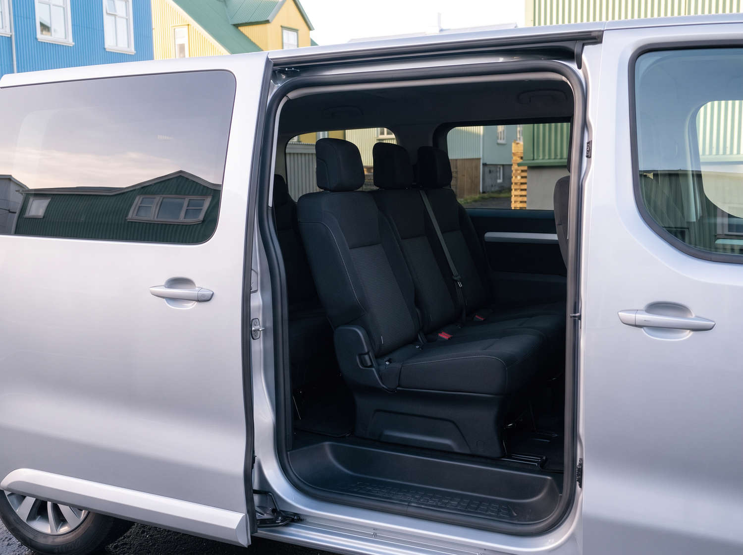 Silver Toyota Proace 9-seater van with automatic transmission, GPS, Bluetooth, heated seats, and USB charger for group travel in Iceland.