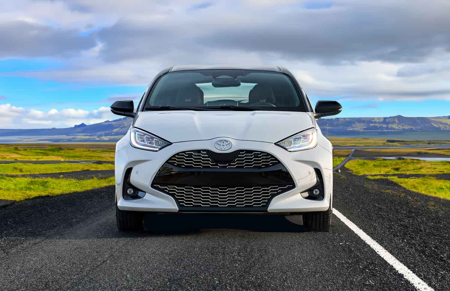 Toyota Yaris hybride rouge avec boîte automatique, 5 places, GPS, caméra de recul et capacité pour 2 bagages, idéale pour voyager en Islande.