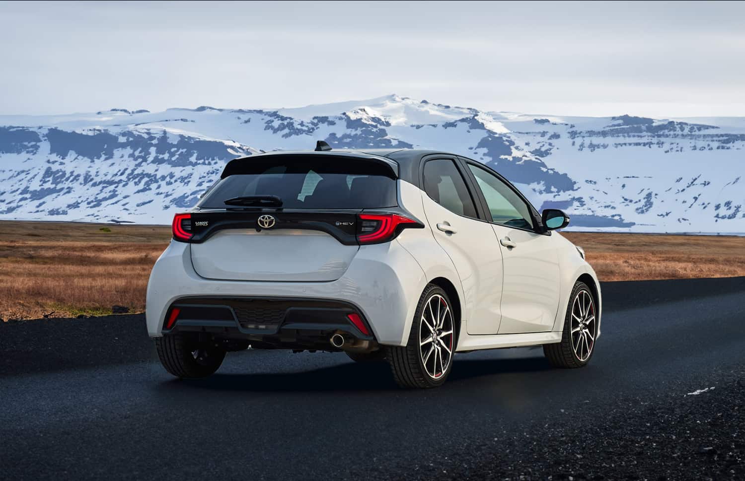 Toyota Yaris hybride rouge avec boîte automatique, 5 places, GPS, caméra de recul et capacité pour 2 bagages, idéale pour voyager en Islande.