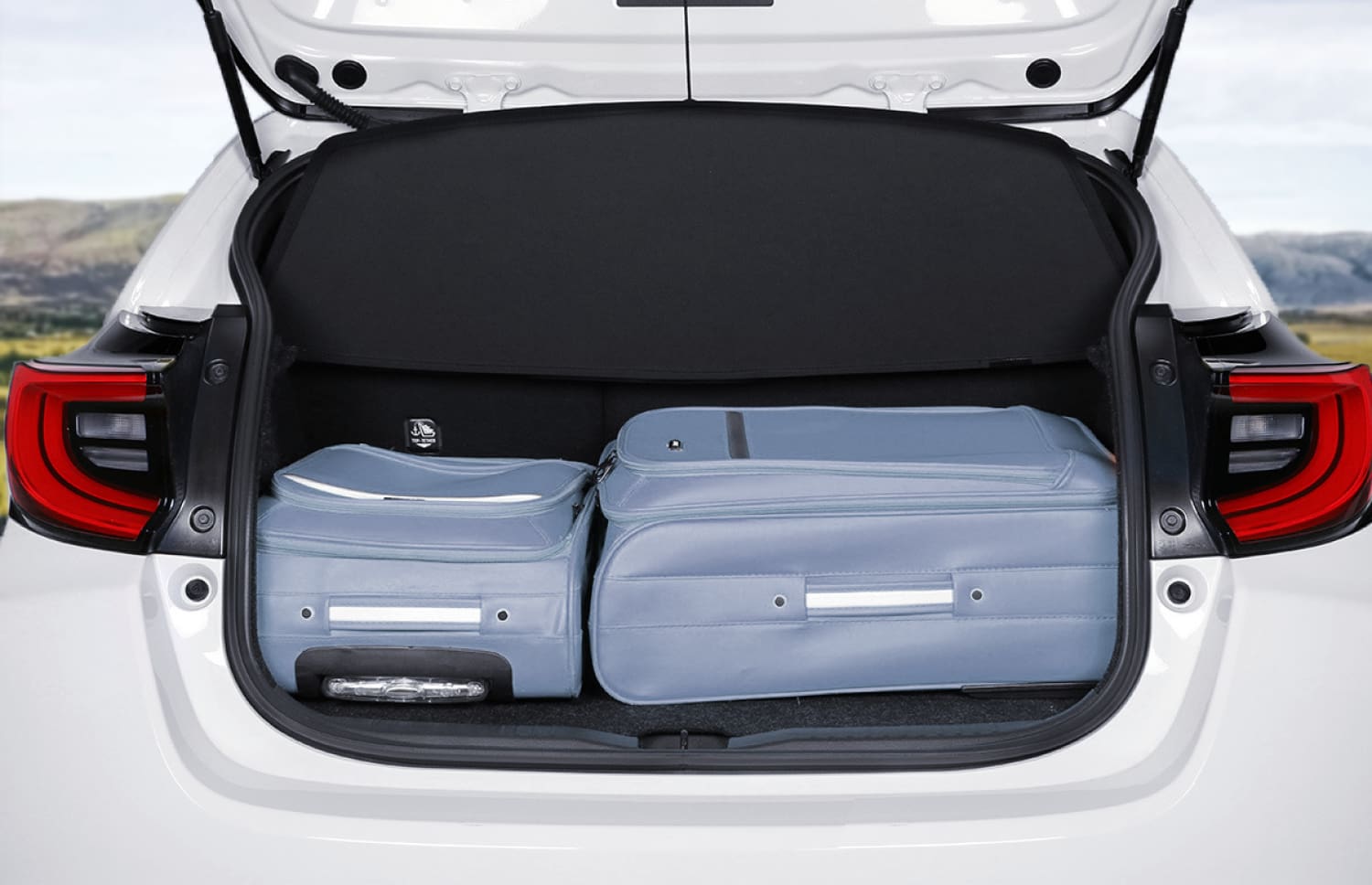 Toyota Yaris hybride rouge avec boîte automatique, 5 places, GPS, caméra de recul et capacité pour 2 bagages, idéale pour voyager en Islande.