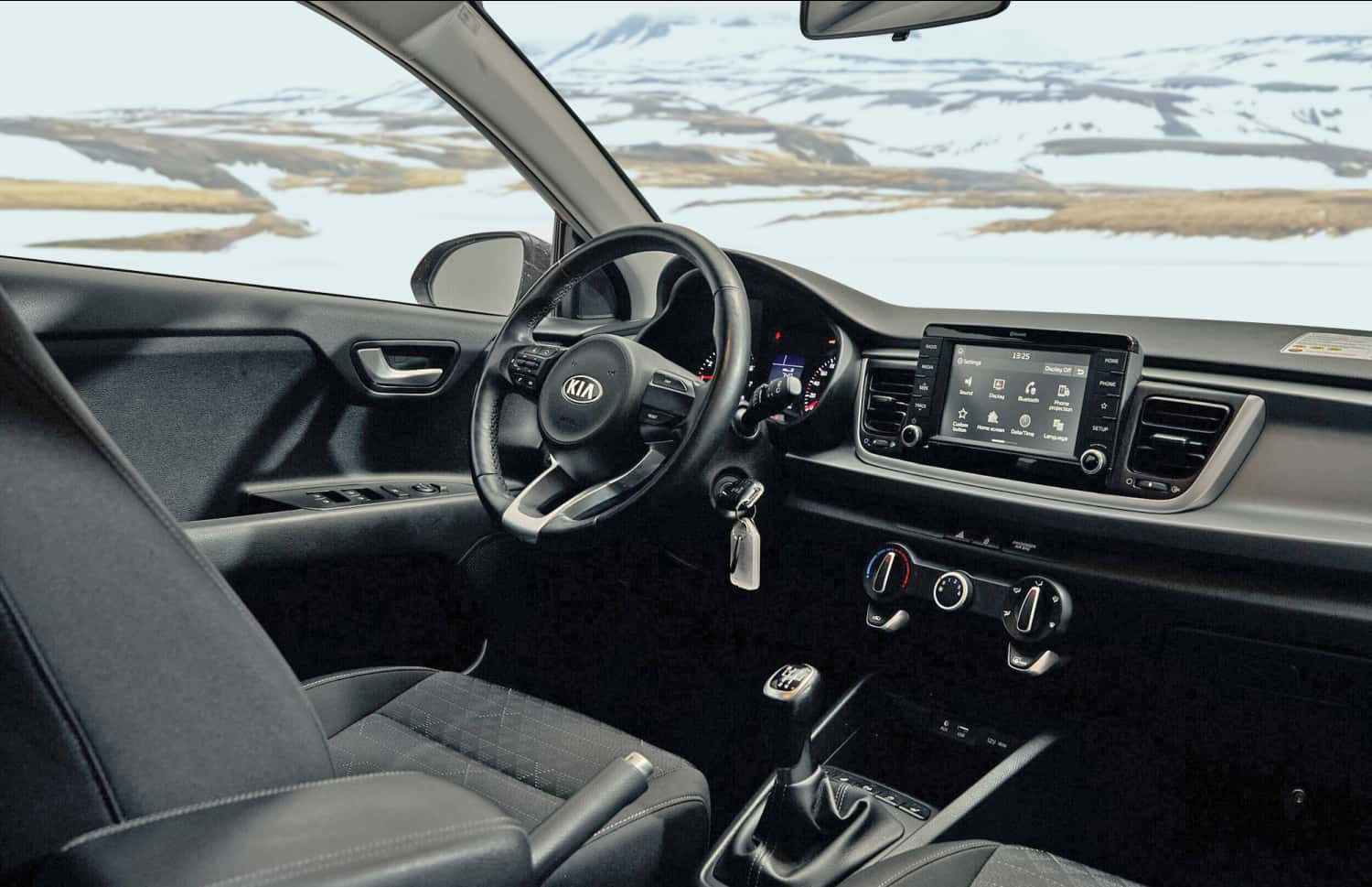 Kia Rio bleue avec boîte manuelle, GPS, caméra de recul et espace pour 5 passagers et 2 bagages, parfaite pour les road trips en Islande.