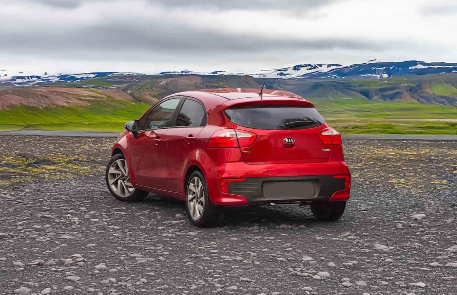 Kia Rio rouge d’occasion avec boîte manuelle, compacte 5 places avec espace pour 2 bagages, parfaite pour un voyage abordable en Islande.