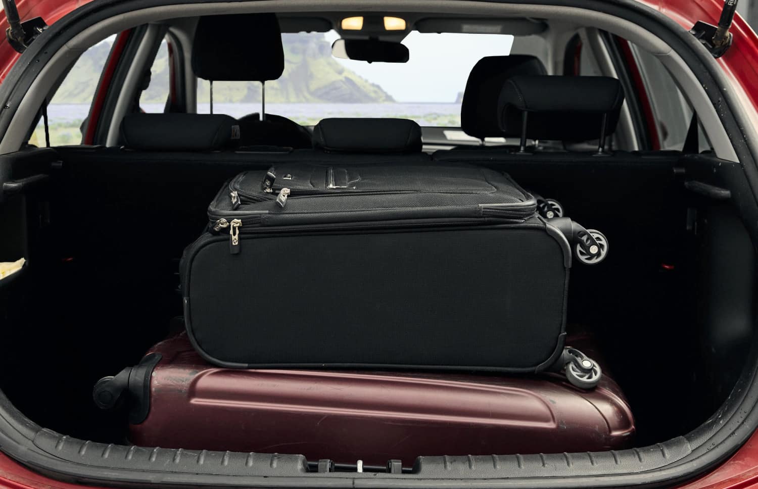 Kia Rio rouge d’occasion avec boîte manuelle, compacte 5 places avec espace pour 2 bagages, parfaite pour un voyage abordable en Islande.