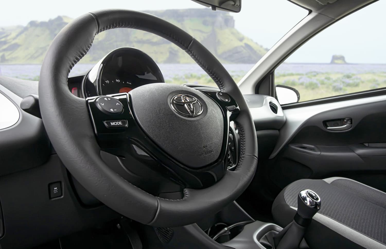 Toyota Aygo compacte gris métallisé avec boîte manuelle, parfaite pour 4 passagers, idéale pour la conduite en ville en Islande.