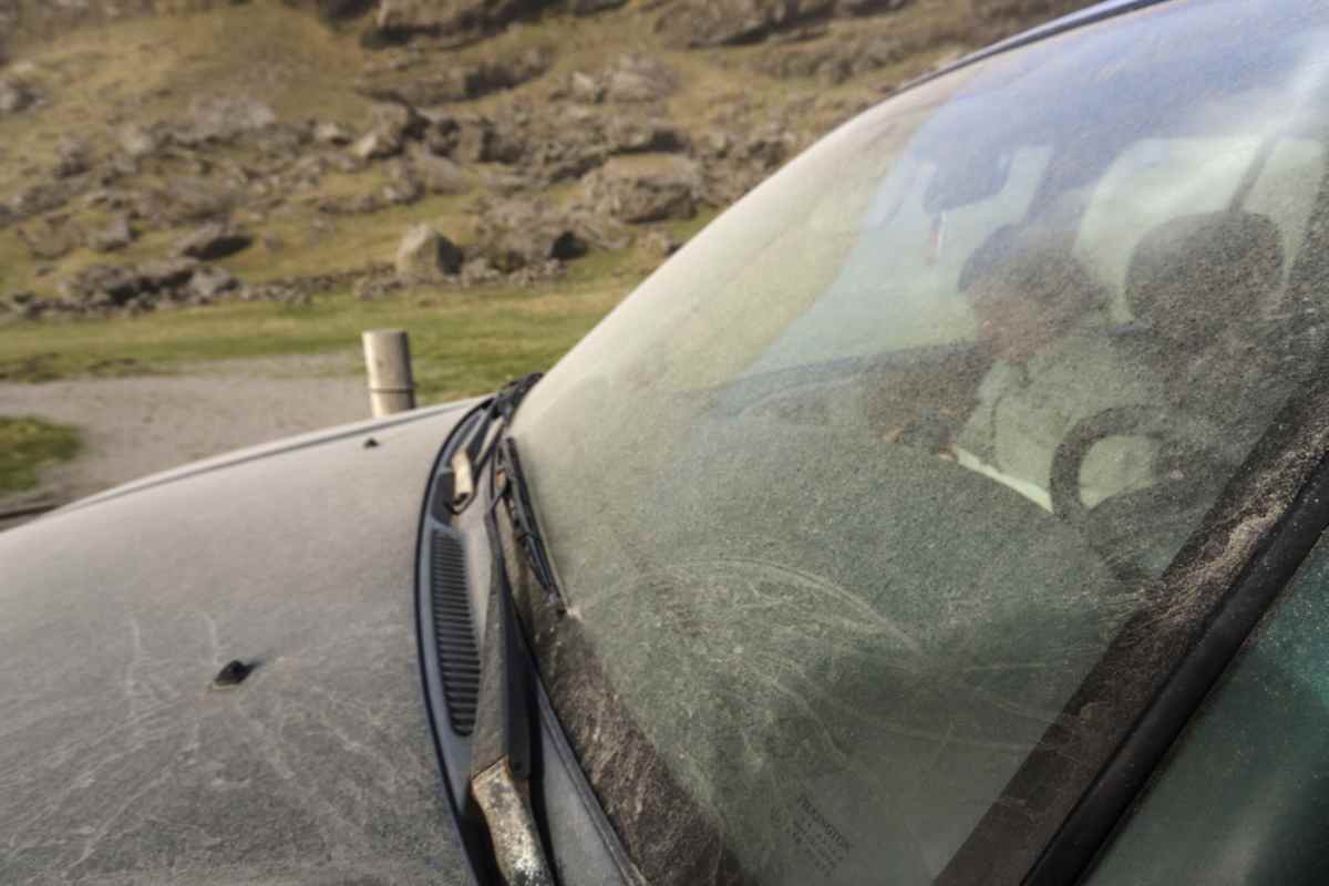 Windschutzscheibe eines Mietwagens in Island, bedeckt mit vulkanischer Asche und Sandschäden.