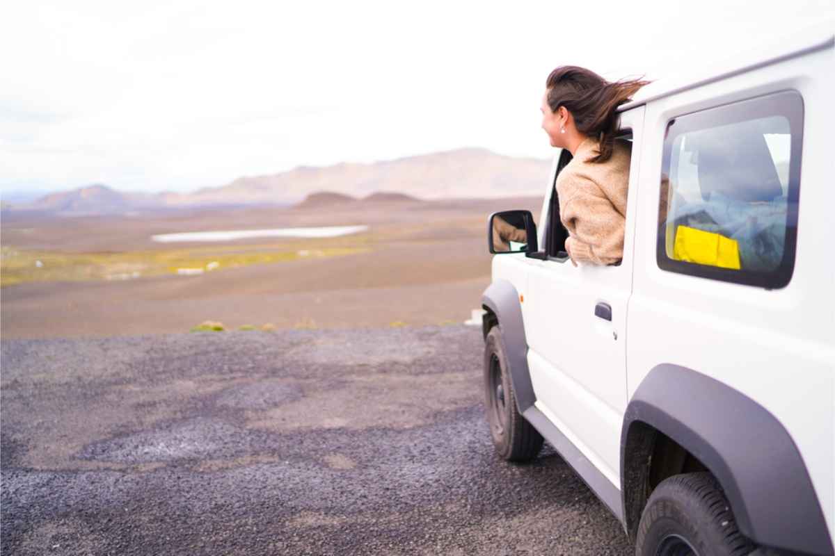 Conductor joven con un coche de alquiler en el paisaje salvaje de Islandia
