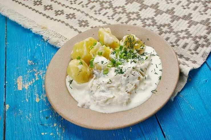 Un plat de ragoût de poisson islandais, accompagné de pommes de terre et d'une sauce crémeuse, présenté sur une assiette beige.