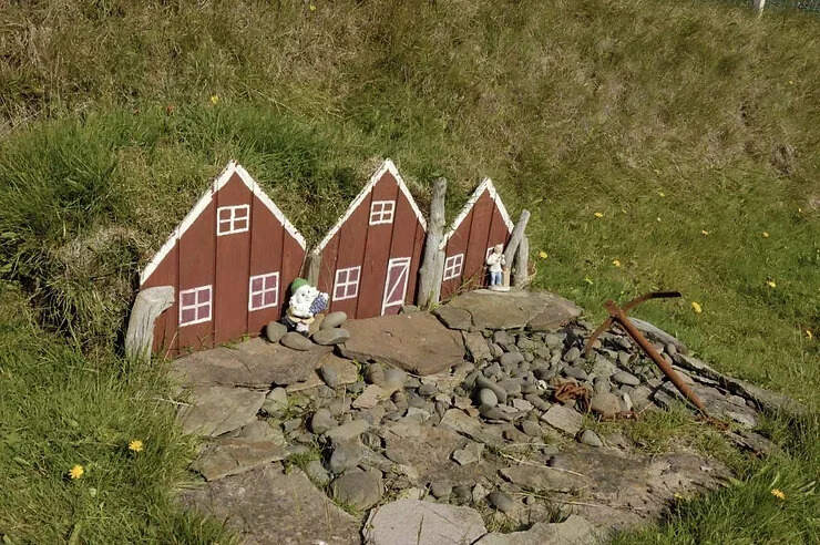 Miniatures de maisons d'elfes islandais nichées dans une colline verdoyante, symbolisant la tradition mythologique et la croyance locale en Islande.