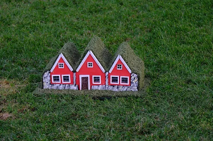Maisons rouges miniatures d'elfes islandais sur une pelouse, illustrant la mythologie et les légendes locales.