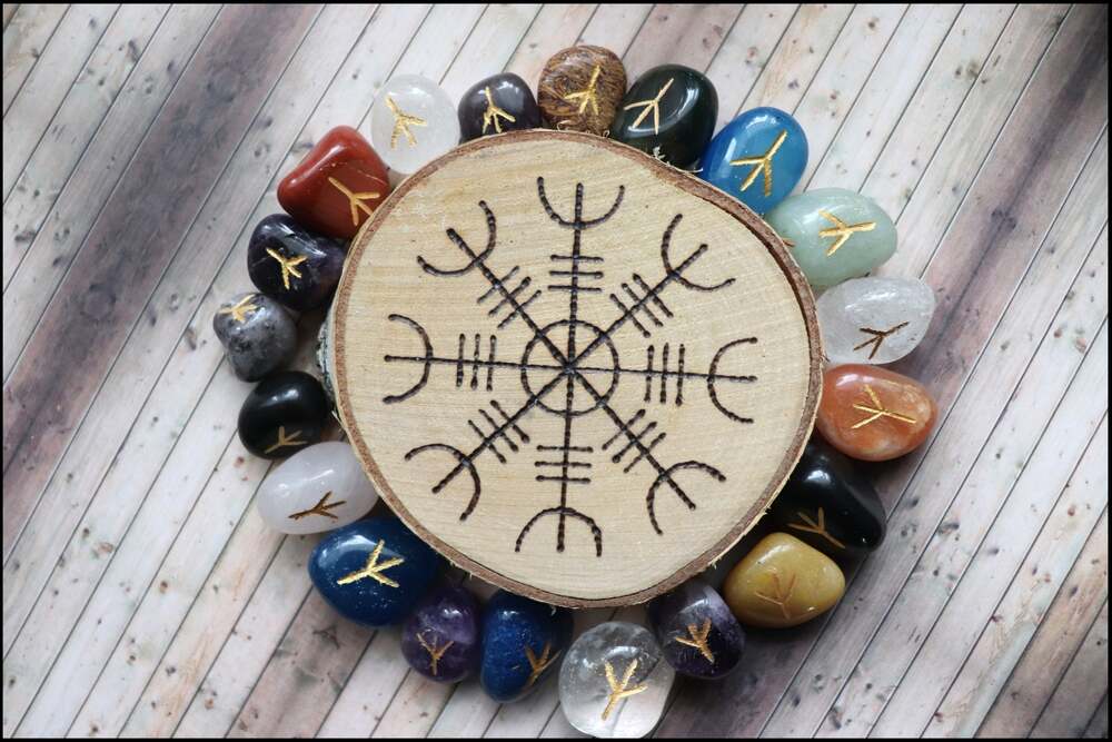 Le symbole Aegishjalmur, une boussole viking, est gravé sur une tranche de bois entourée de pierres précieuses de couleur gravées de runes d'or.