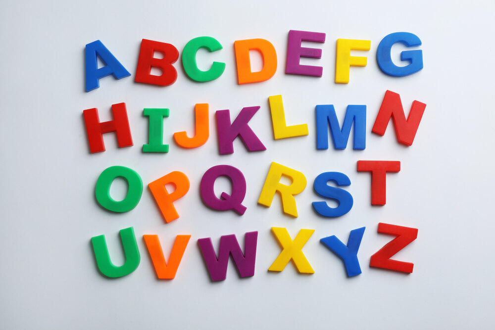 Lettres majuscules multicolores de l'alphabet, disposées sur une surface blanche, utilisées pour des jeux éducatifs ou l'apprentissage.