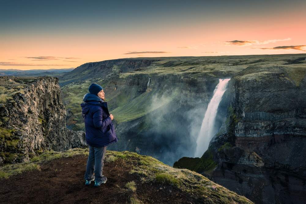 Exploration de Haifoss - Randonnée avec vue imprenable sur la cascade. Un randonneur contemplant la cascade Haifoss au lever du jour, entouré d'un paysage volcanique.