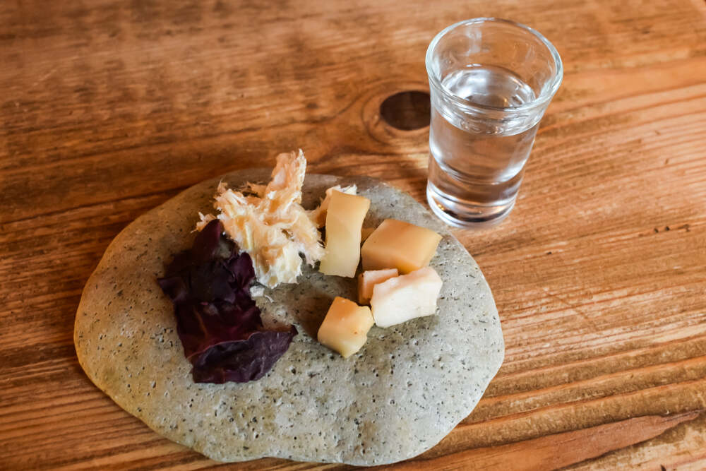 Assiette de dégustation traditionnelle islandaise avec hákarl, algues et fromage. Un plat traditionnel islandais composé de morceaux de requin fermenté, d'algues séchées et de fromage disposés sur une galette avec un verre d'eau-de-vie claire.