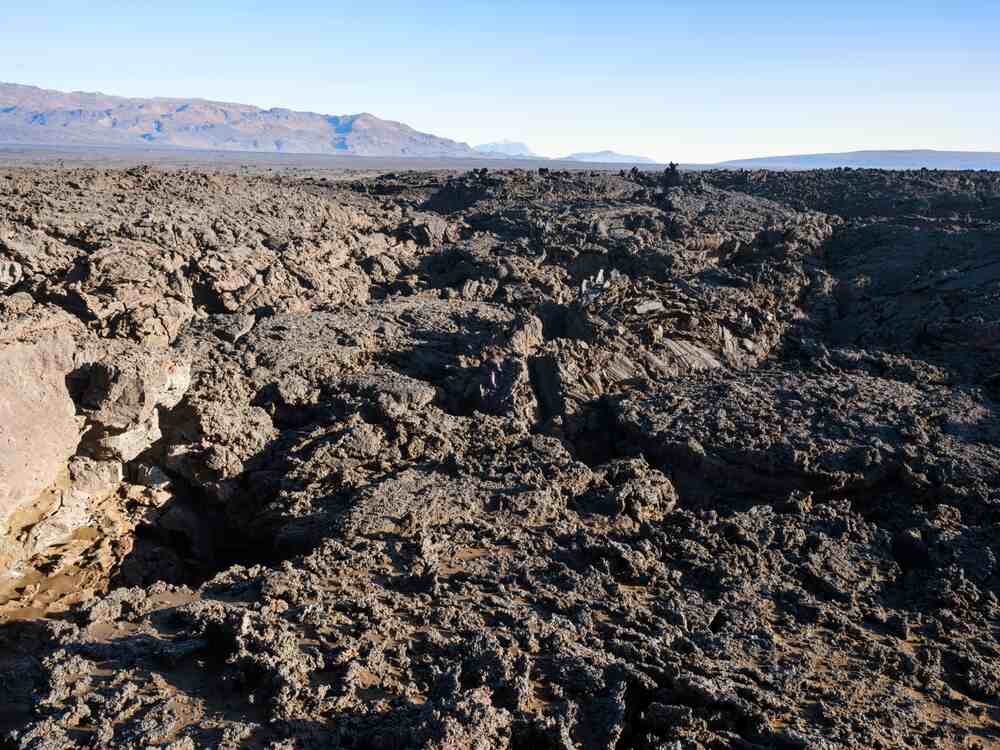 Champ de lave de Holuhraun - Terre volcanique de l'Islande. Étendue de lave noire et rugueuse à Holuhraun, formant un paysage volcanique aride sous un ciel dégagé, symbole des forces telluriques de l'Islande.