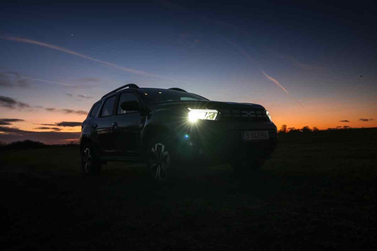 Gros plan d’un véhicule Dacia Duster dans une zone non urbaine au coucher du soleil.