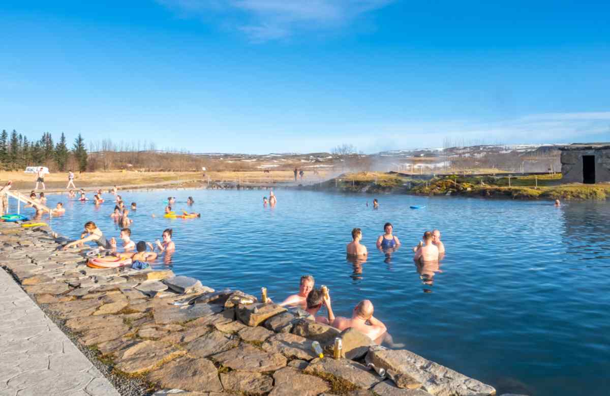 Des dizaines de personnes profitent d’une belle journée ensoleillée en Islande à la Lagune Secrète.