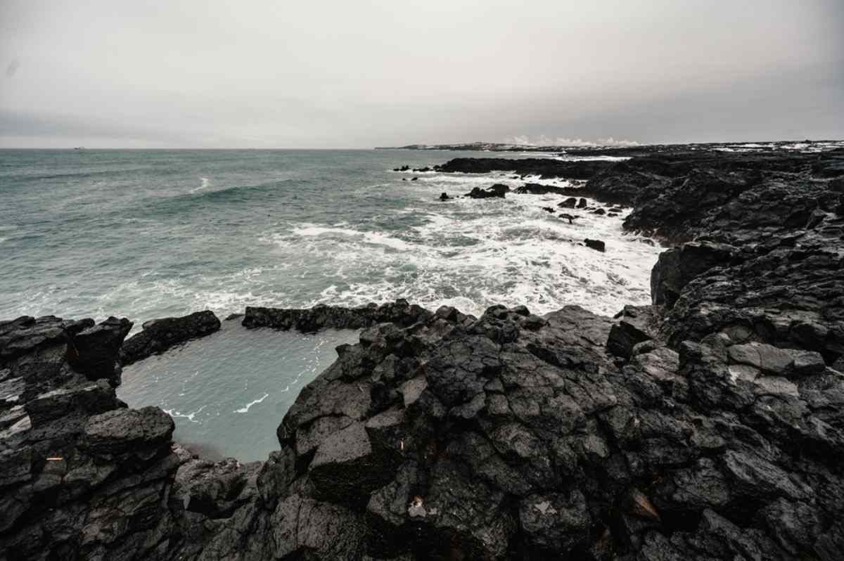 Vue drone d’un bassin rocheux en Islande près de l’océan Atlantique lors d’une journée nuageuse.