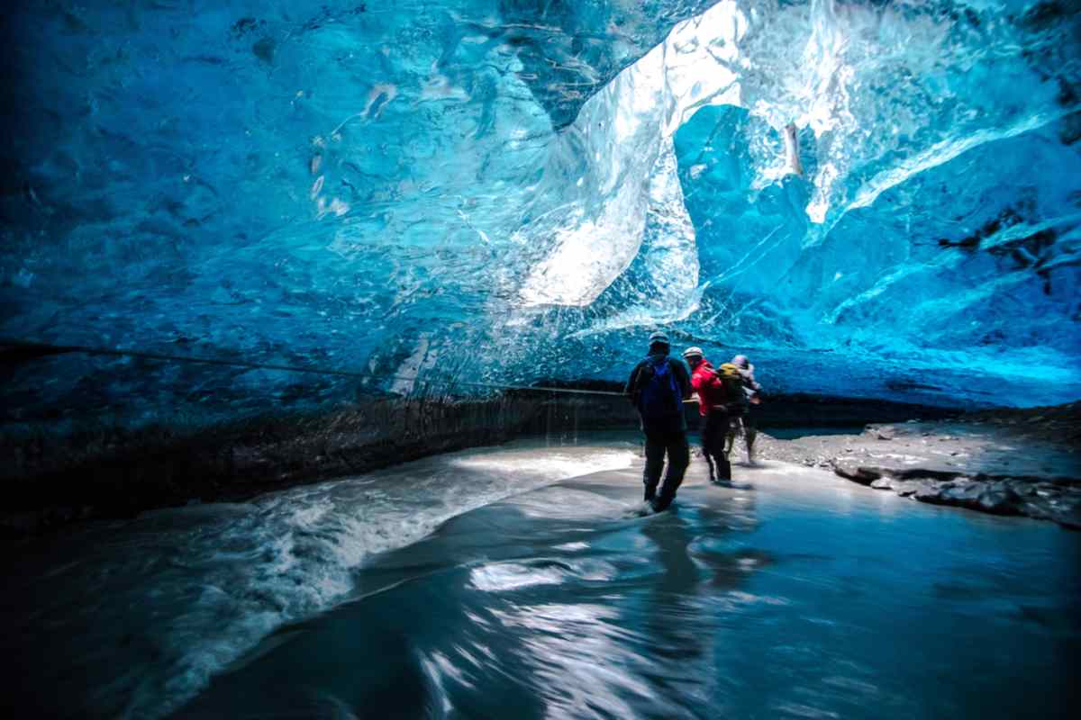 Un petit groupe de personnes profitant d’une visite dans une grotte de glace en Islande avec des précautions de sécurité extrêmes.