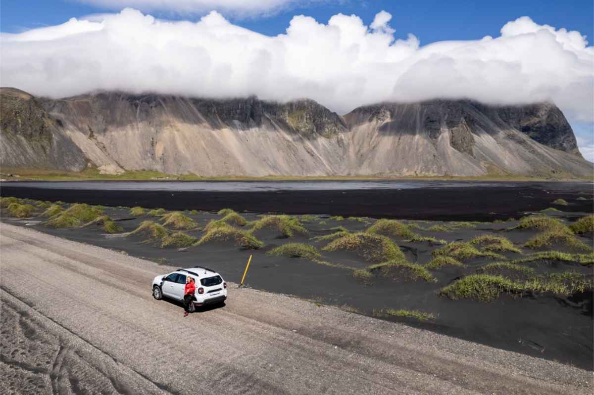 Conducente solitario appoggiato alla sua Dacia Duster parcheggiata vicino a Vestrahorn