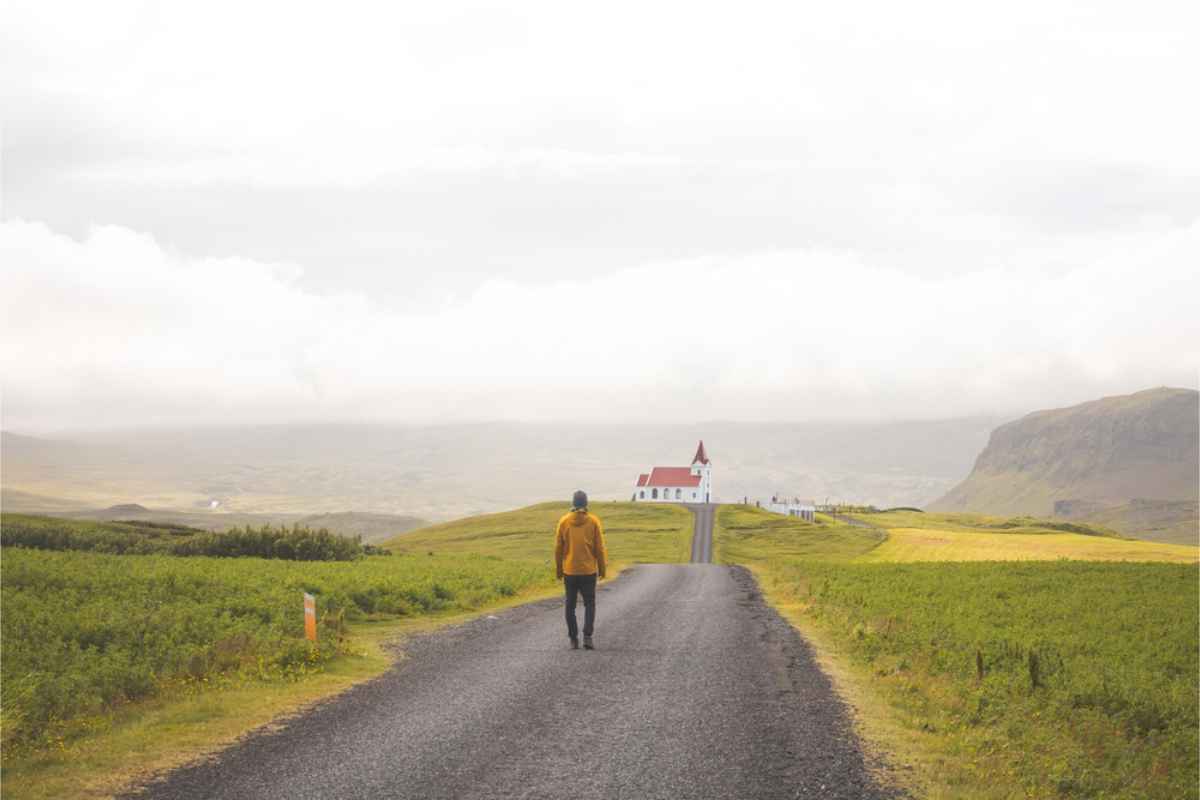 Uomo in solitaria che sale verso una chiesa in cima a una collina